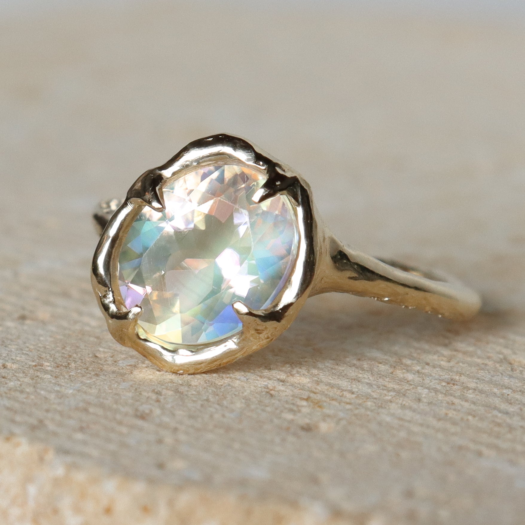 Gold ring with a large, faceted gemstone on a beige background