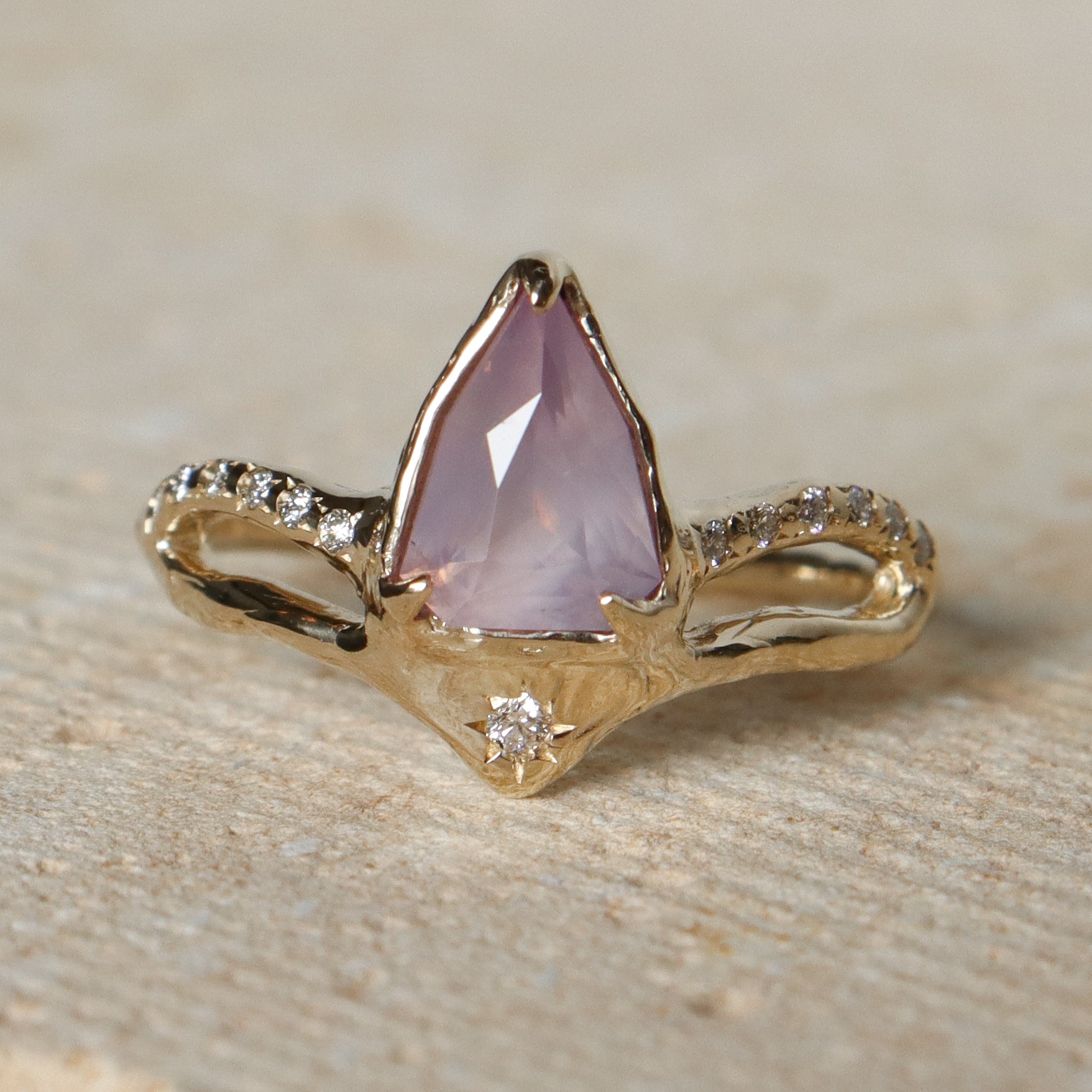 Gold ring with a pink gemstone on a stone surface