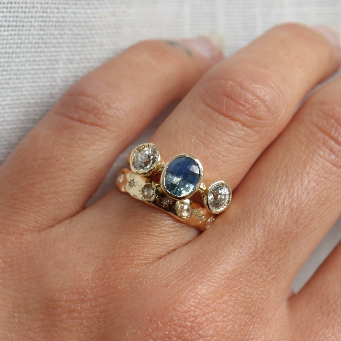Gold ring with a blue gemstone and diamonds on a person&