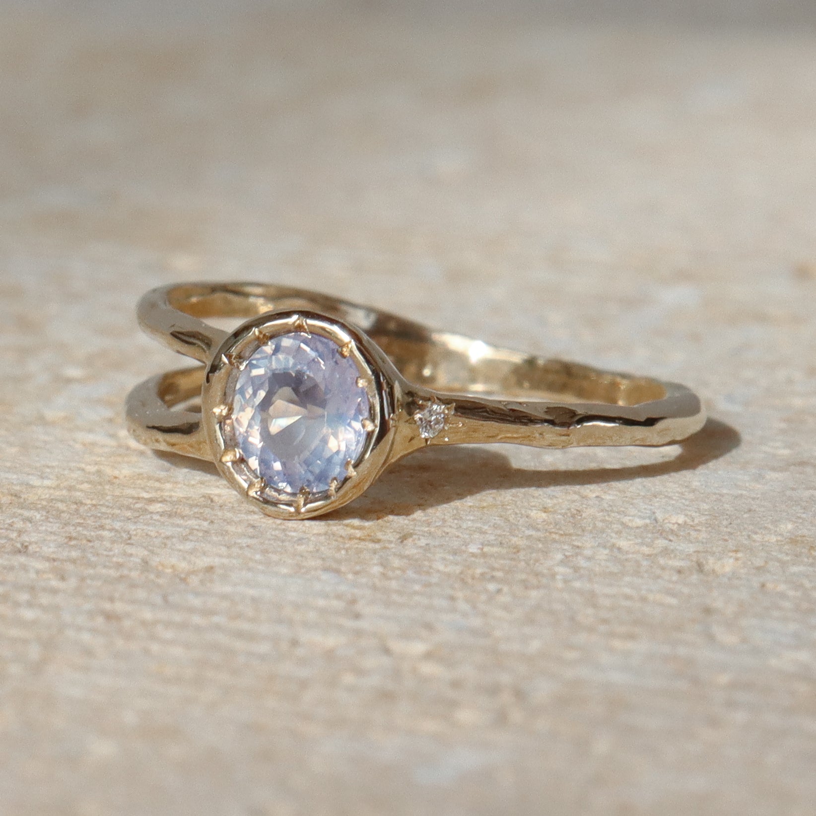 Gold ring with a clear gemstone on a beige textured background