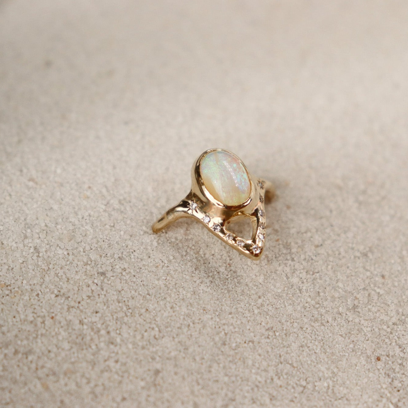 A partial side view of an elegant opal ring featuring a V-shaped design adorned with sparkling diamond accents