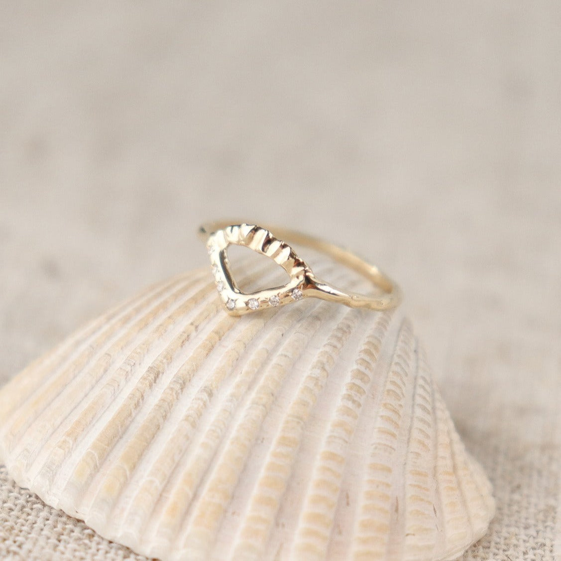Elegant gold ring with V-shaped diamond detail and arched fin texture.