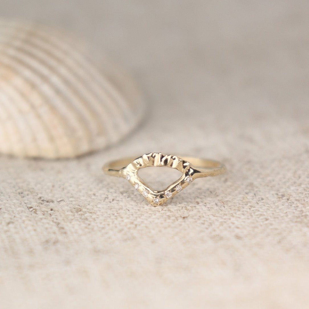 Elegant gold ring with V-shaped diamond detail and arched fin texture.
