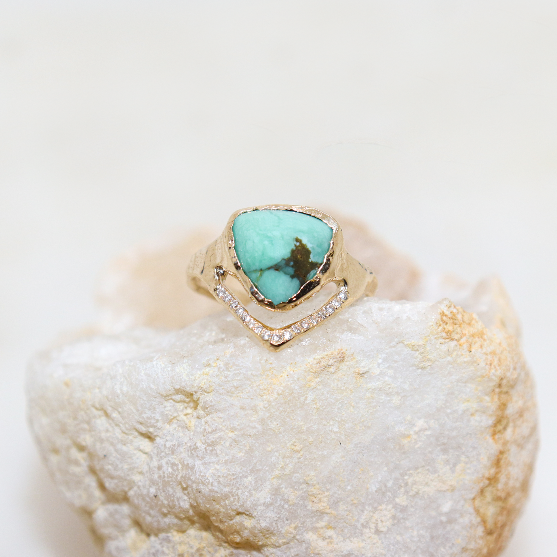 A trillion variscite is bezel set in 14k yellow gold with a v-shape band covered in pave diamonds