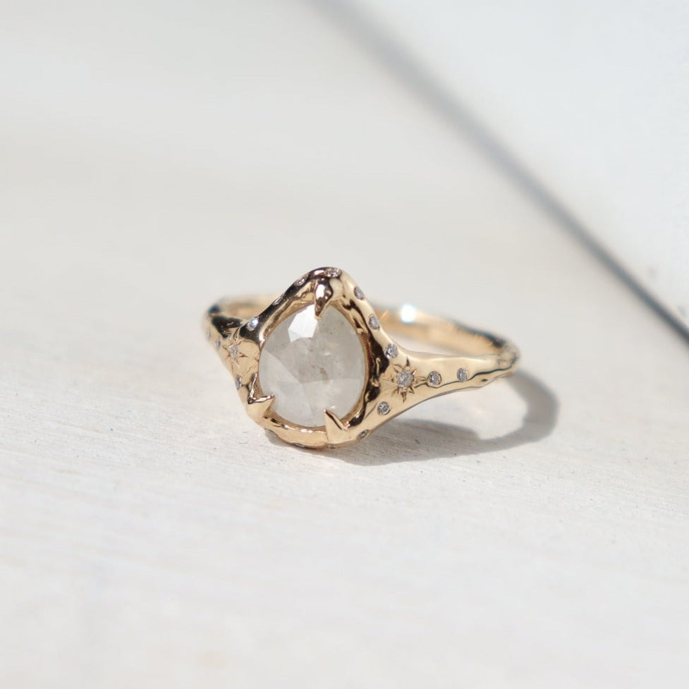 close up of a white icy diamond prong set in gold and surrounded by flush set diamonds