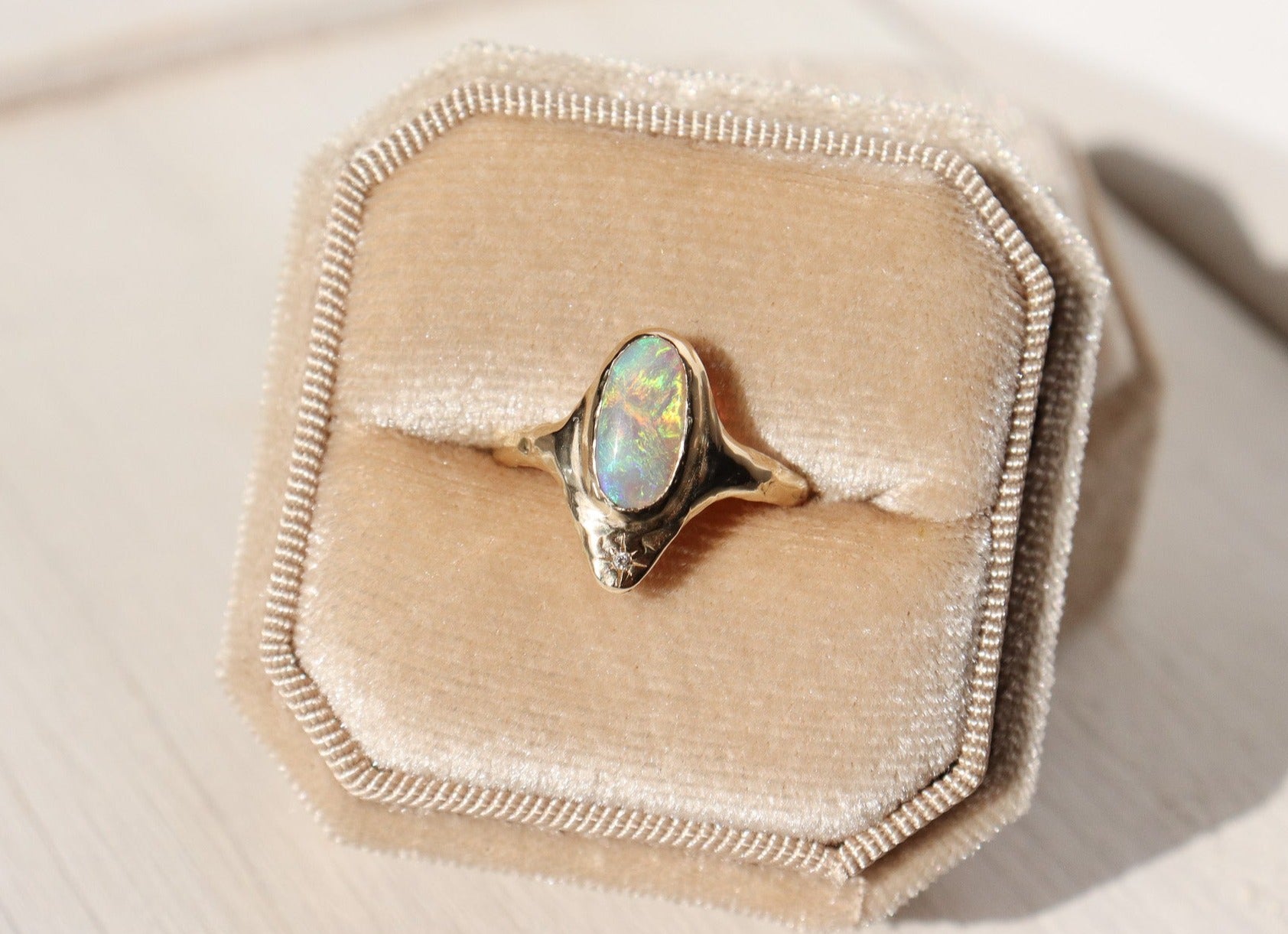 A long oval opal is bezel set in 14k gold  with  a star set  diamond at the base of the ring.