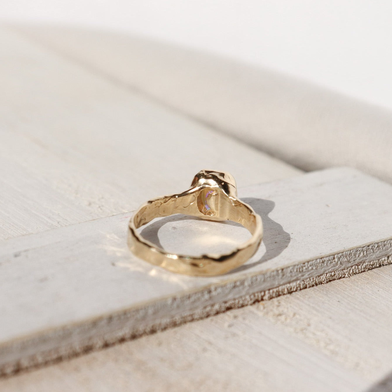 An emerald cut opal is bezel set in 14k gold with a wide band that features ombre sapphires star set a long each side of the band.