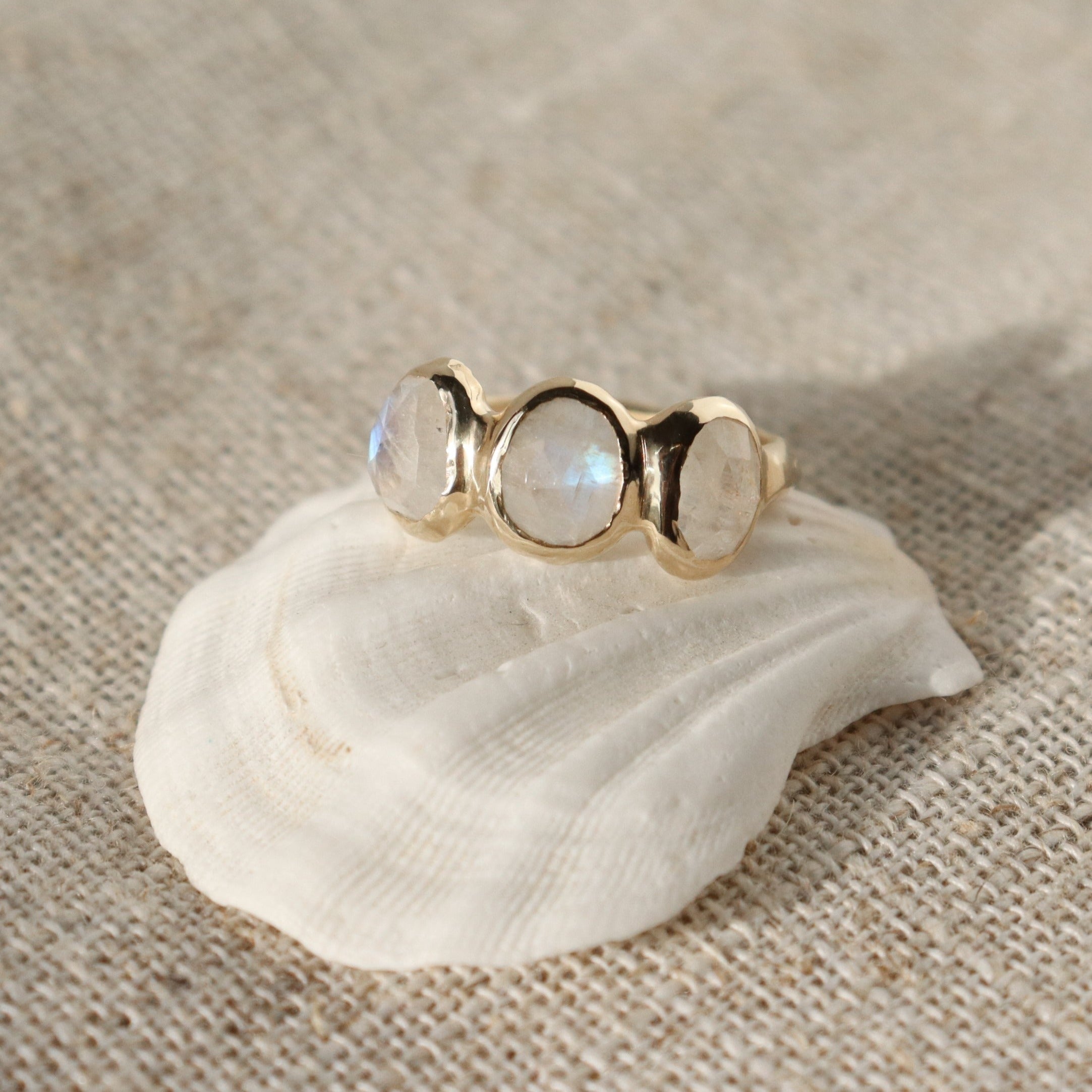 Three rose cut moonstones are bezel set in 14k gold across the front of an organic band.