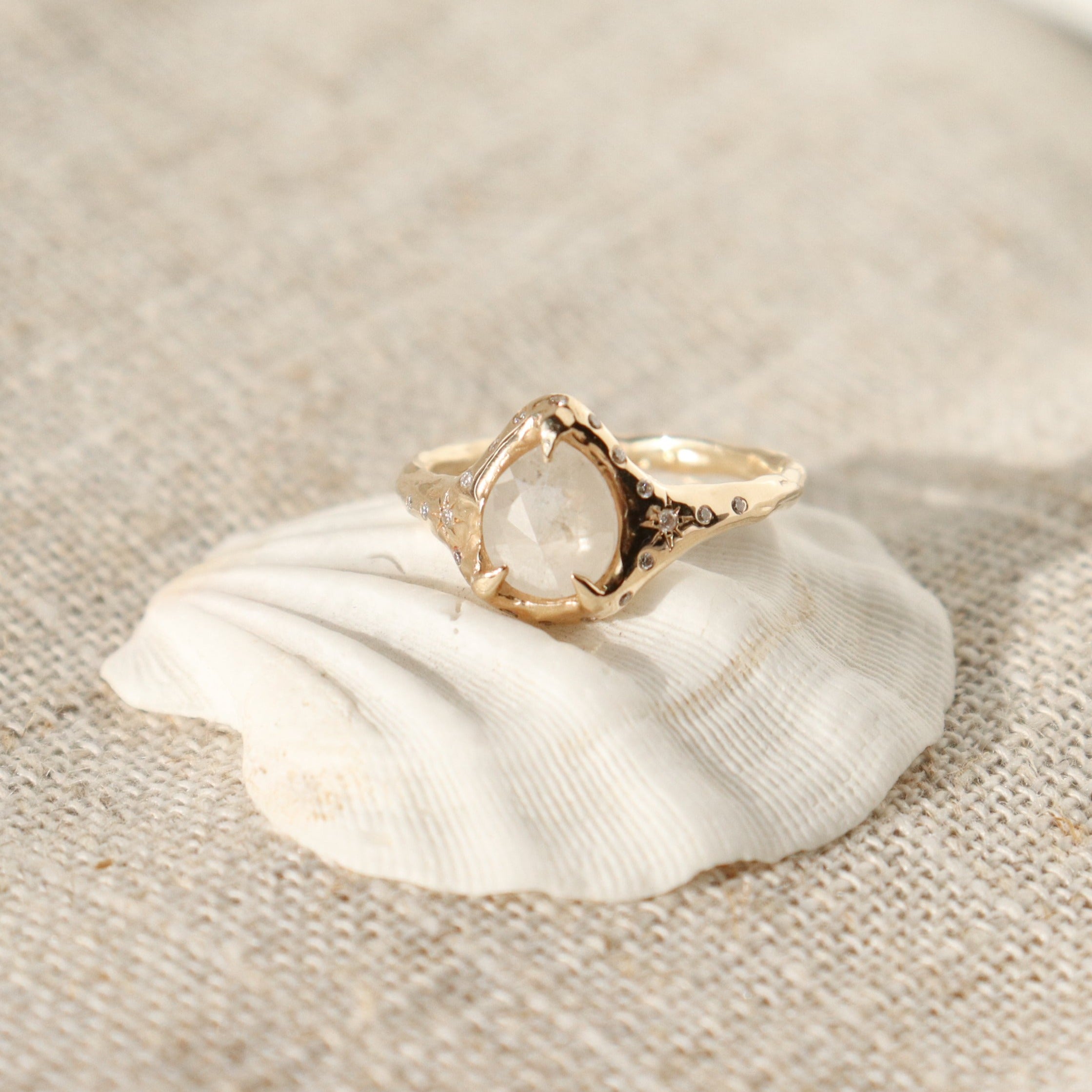 A pear shaped icy diamond is set with prongs and surrounded by diamonds on a 14k gold band.