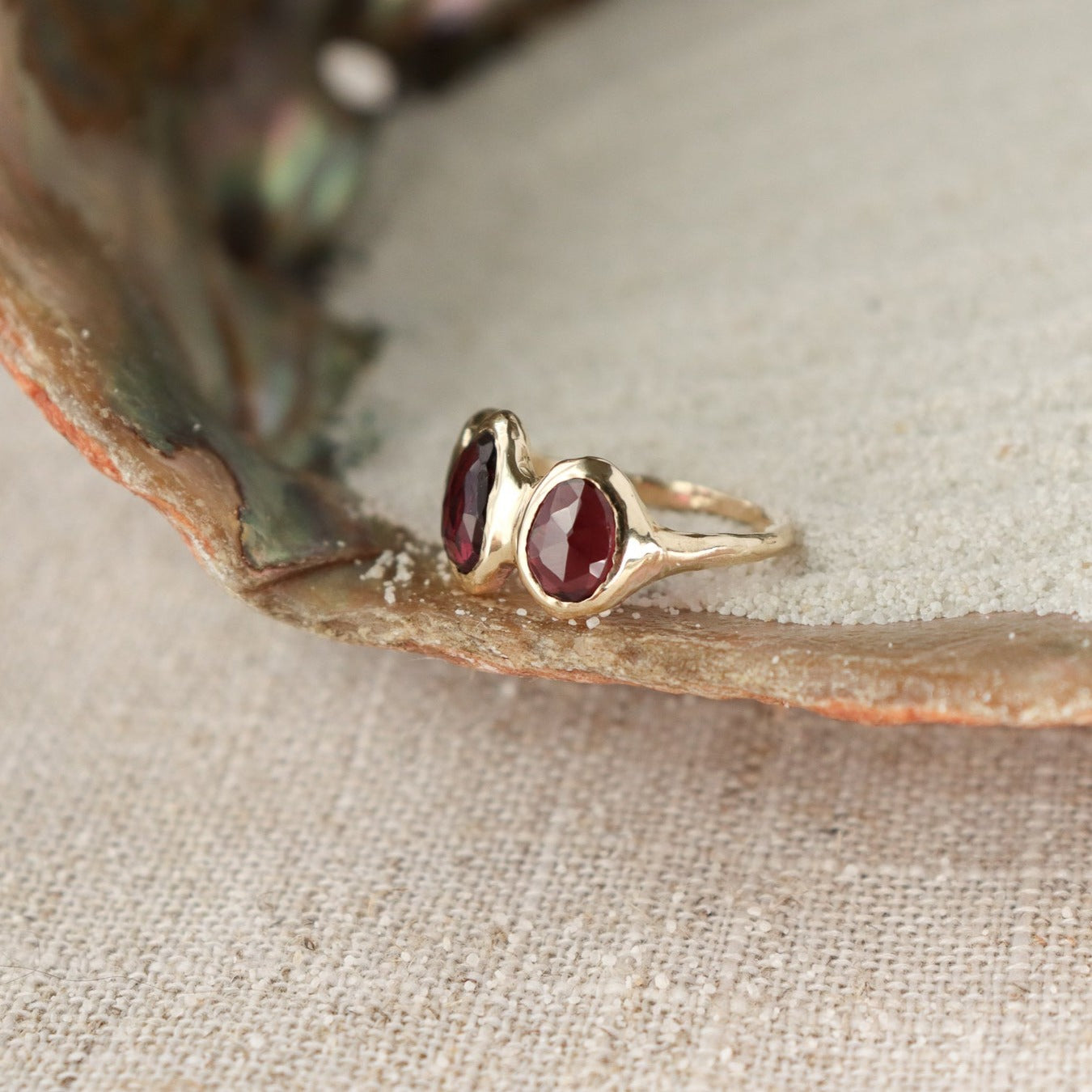 Three rose cut rhodolite garnets are bezel set on an organically crafted 14k gold band.