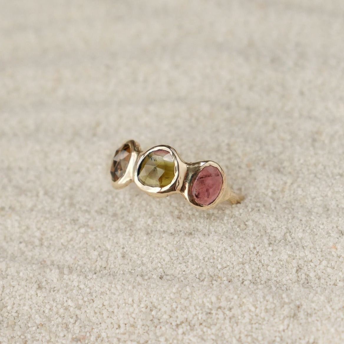 Watermelon tourmaline gemstones are bezel set along the front of a 14k gold band.