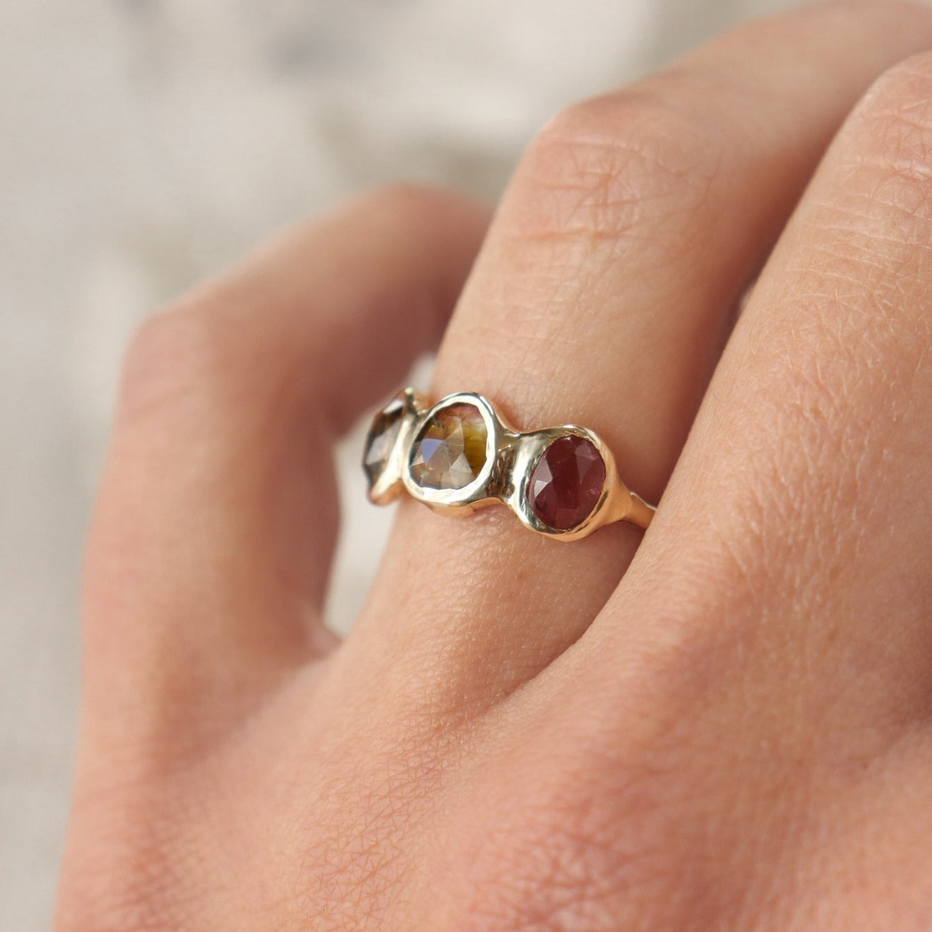 Watermelon tourmaline gemstones are bezel set along the front of a 14k gold band.