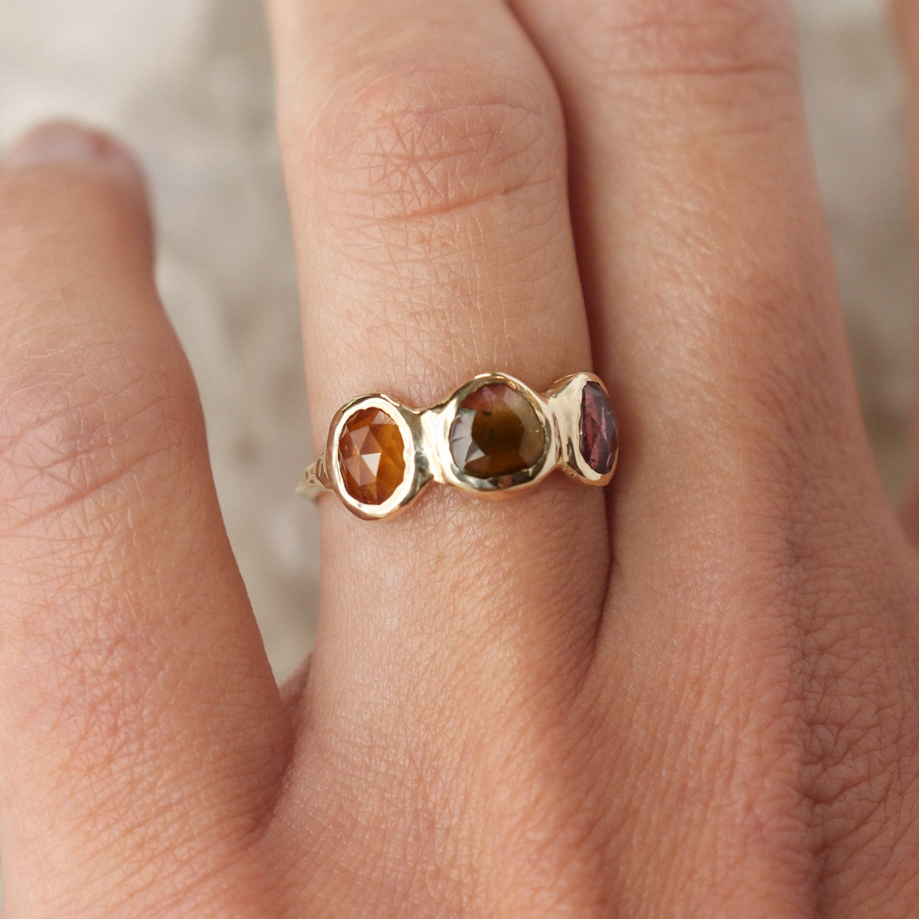 Watermelon tourmaline gemstones are bezel set along the front of a 14k gold band.