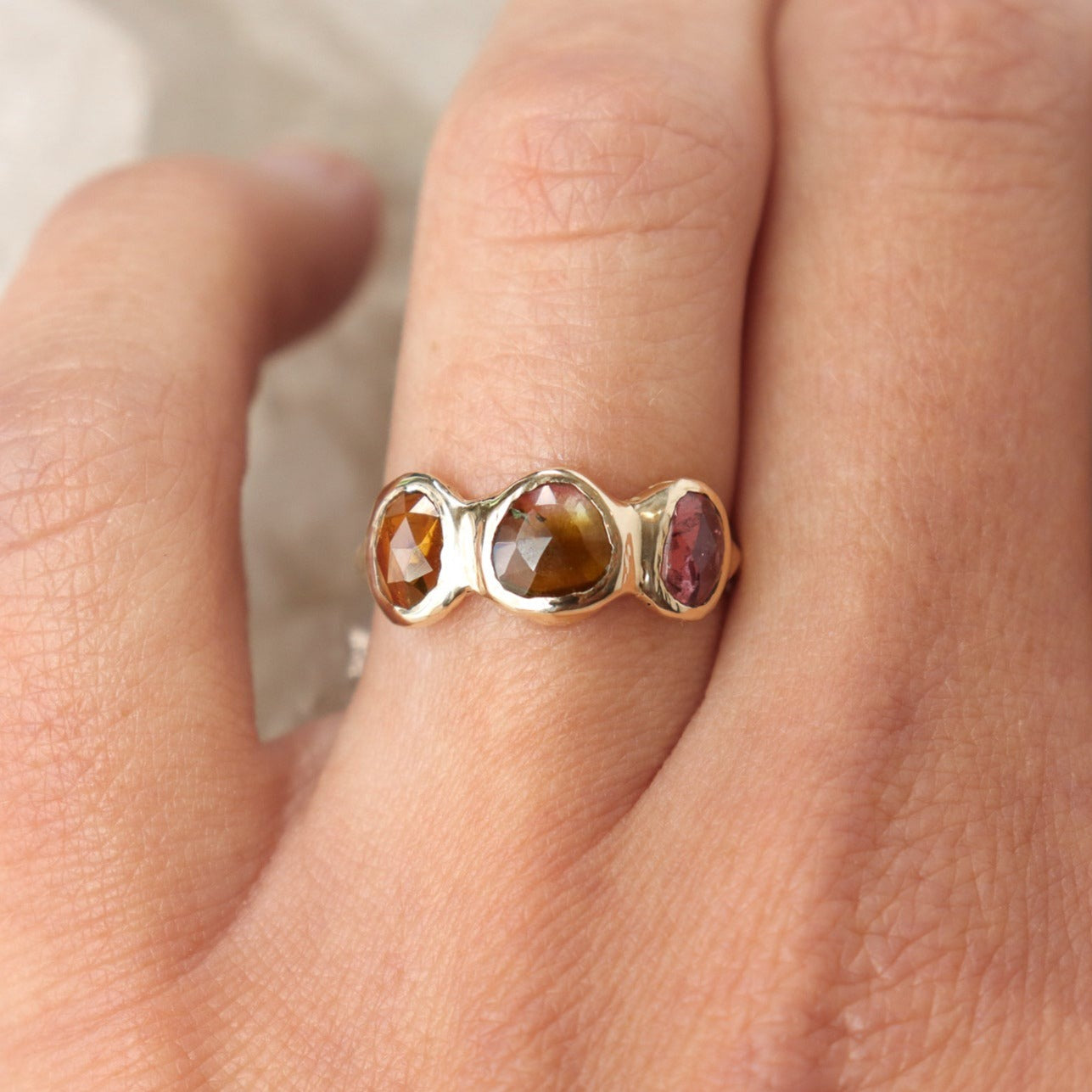 Watermelon tourmaline gemstones are bezel set along the front of a 14k gold band.