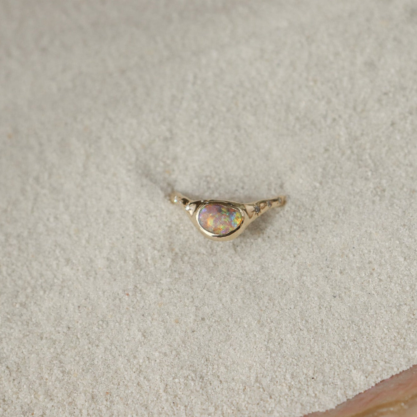 A  crystal boulder opal is bezel set on an  organically crafted band with three star set diamonds on each side of the stone.