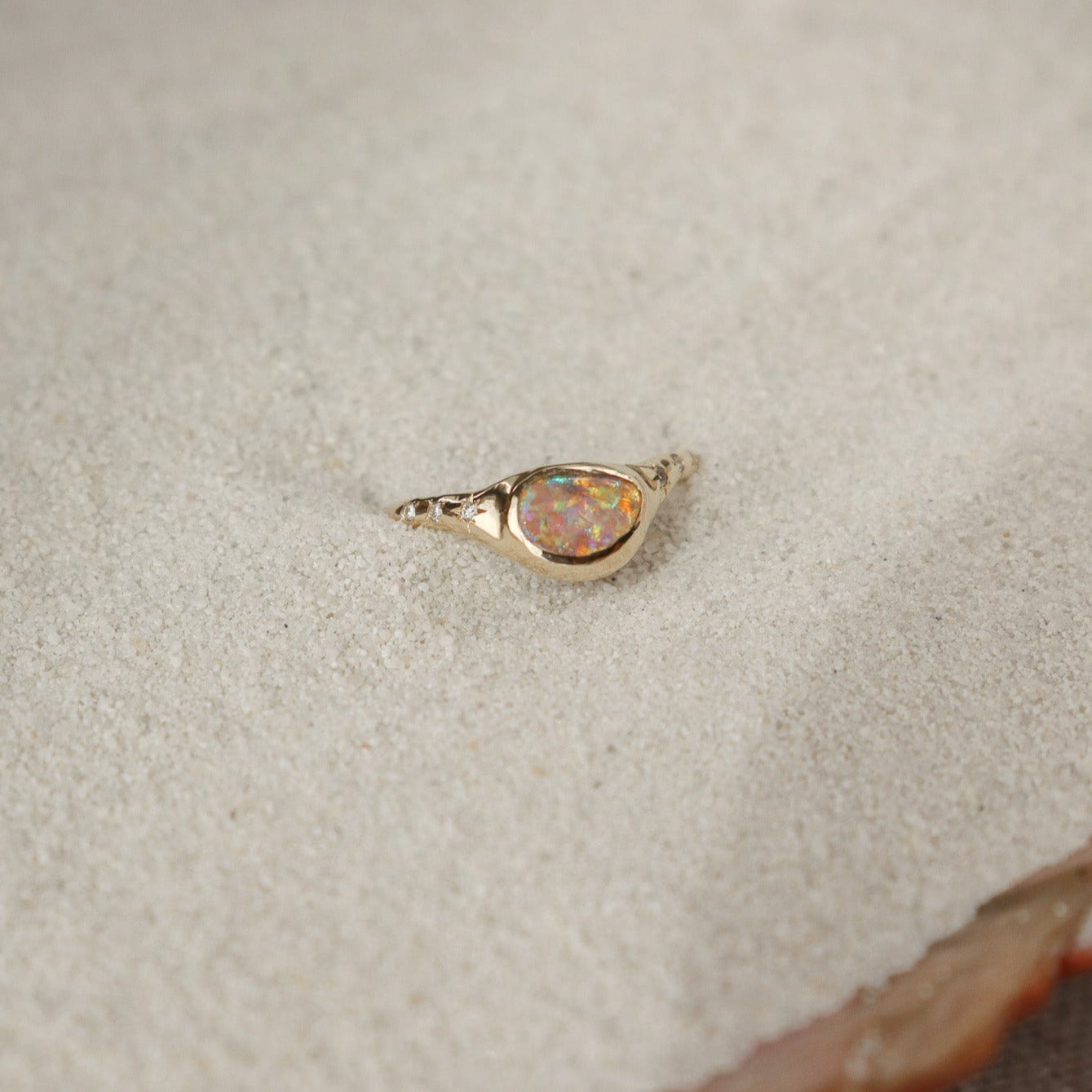 A  crystal boulder opal is bezel set on an  organically crafted band with three star set diamonds on each side of the stone.