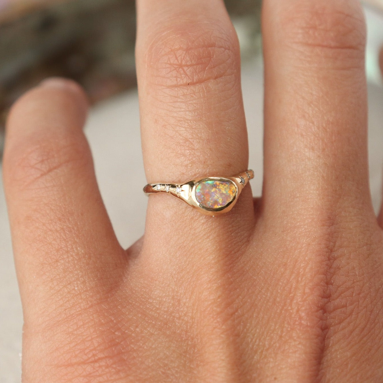 A  crystal boulder opal is bezel set on an  organically crafted band with three star set diamonds on each side of the stone.