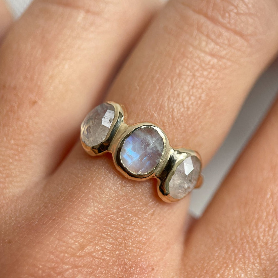 Three rose cut moonstones are bezel set in 14k gold across the front of an organic band.