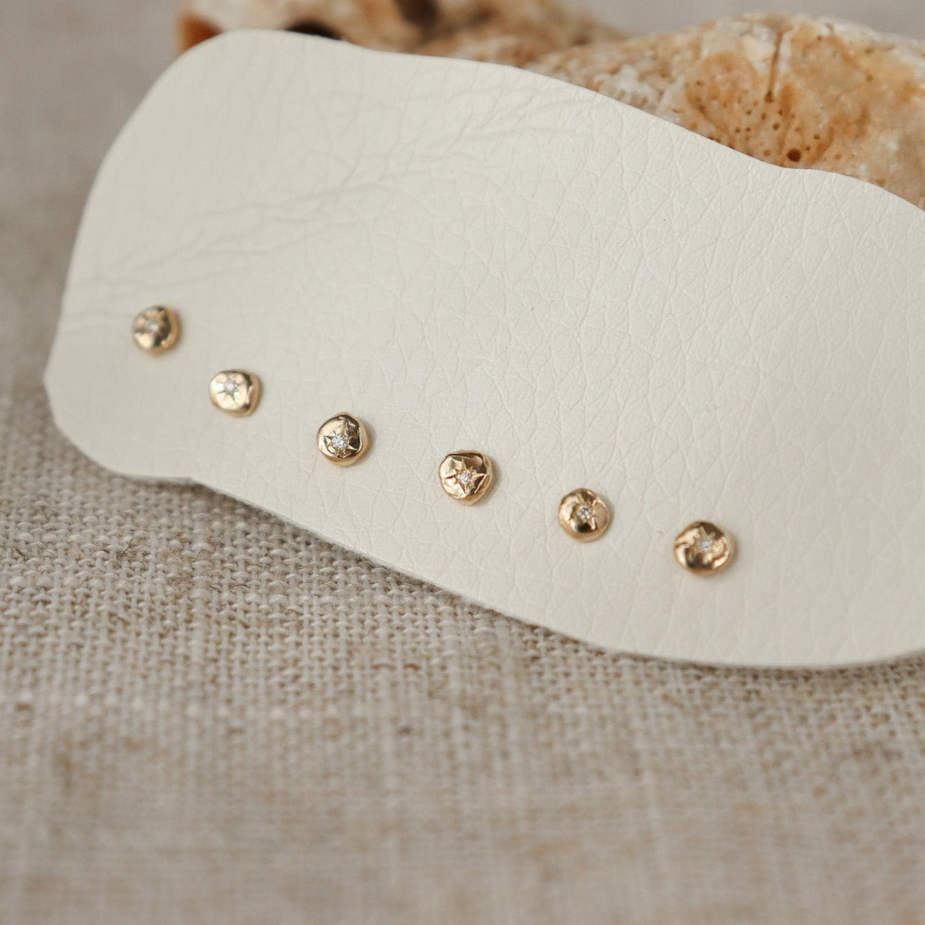 Multiple one of a kind tiny 14k gold circle studs with star set diamonds in the centers.