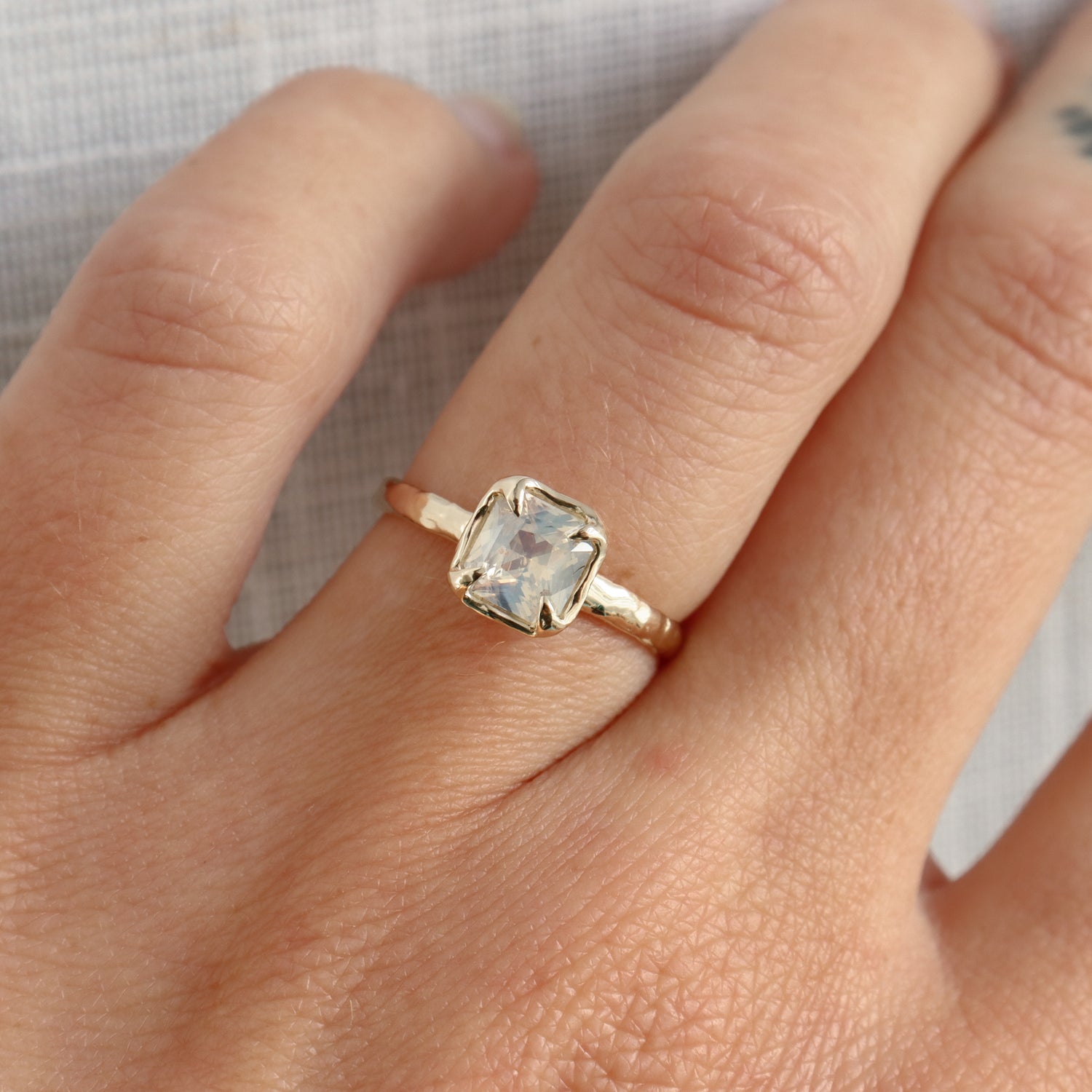 Gold ring with a clear gemstone on a person&