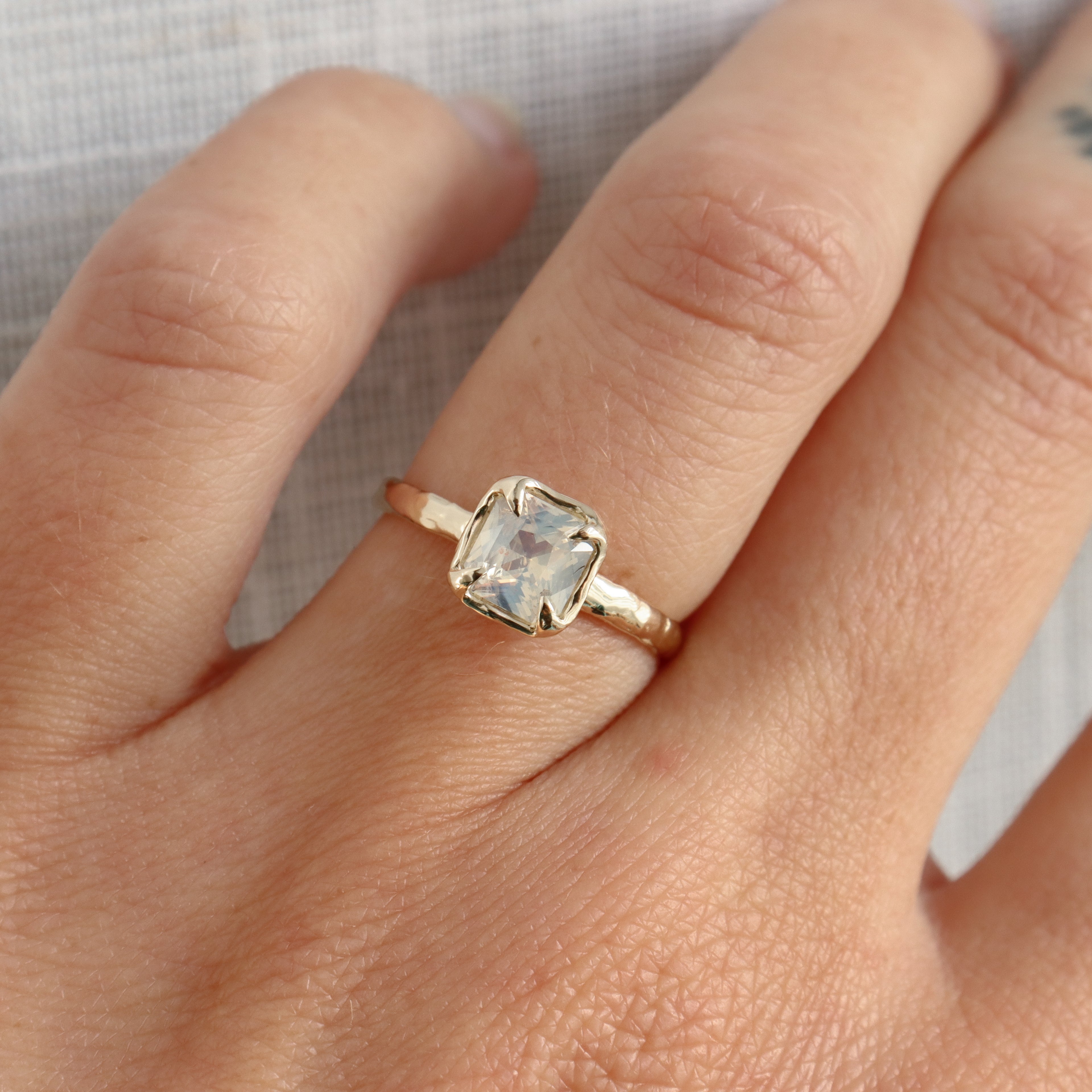 Gold ring with a clear gemstone on a person&