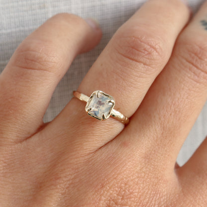 Gold ring with a clear gemstone on a person&