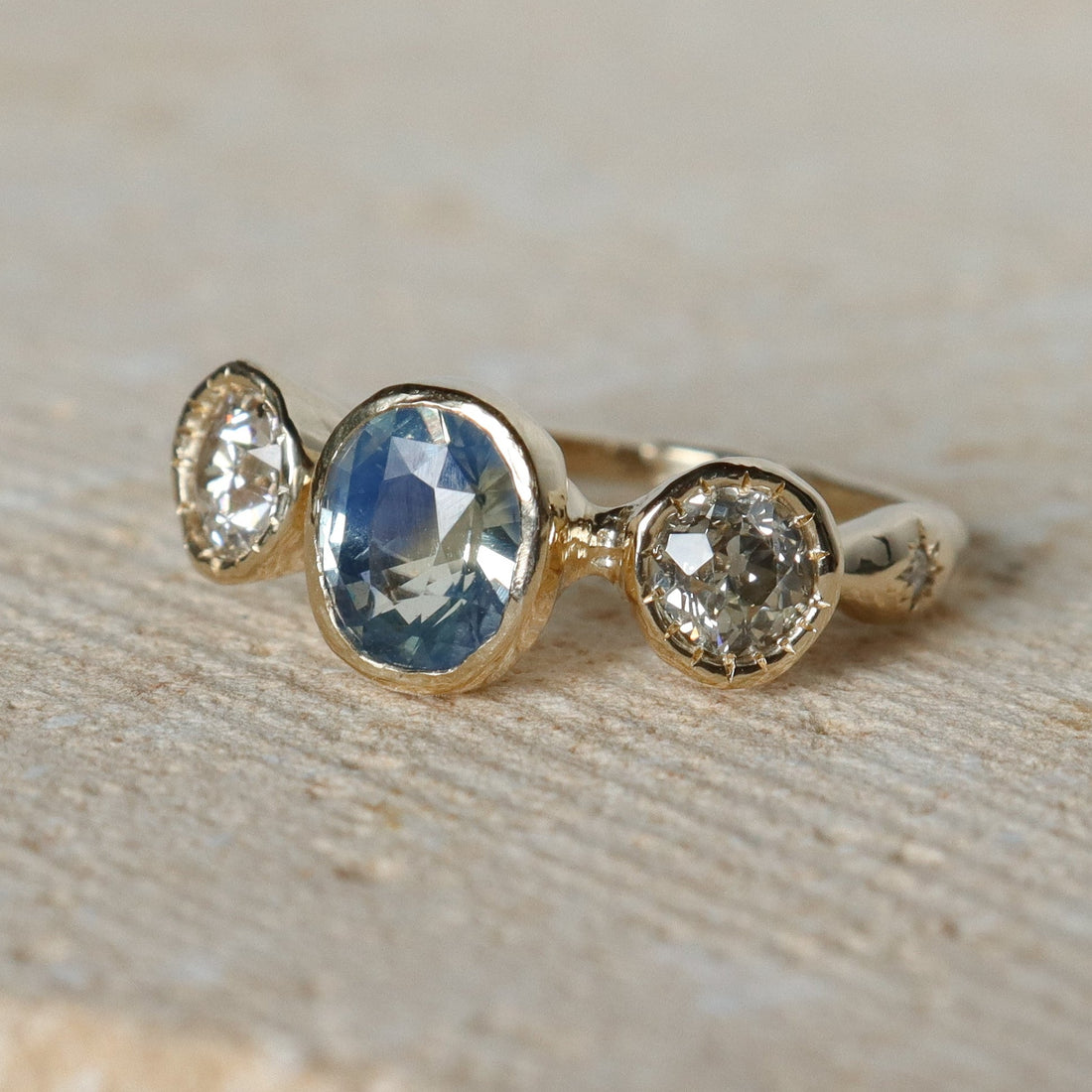 Gold ring with three gemstones on a beige background