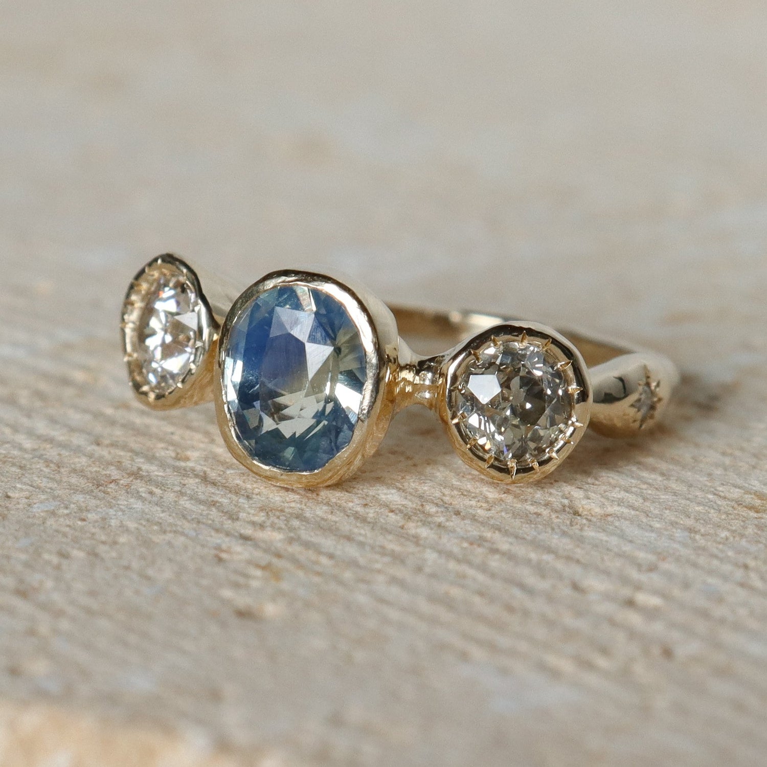 Gold ring with three gemstones on a beige background