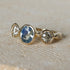 Gold ring with three gemstones on a beige background