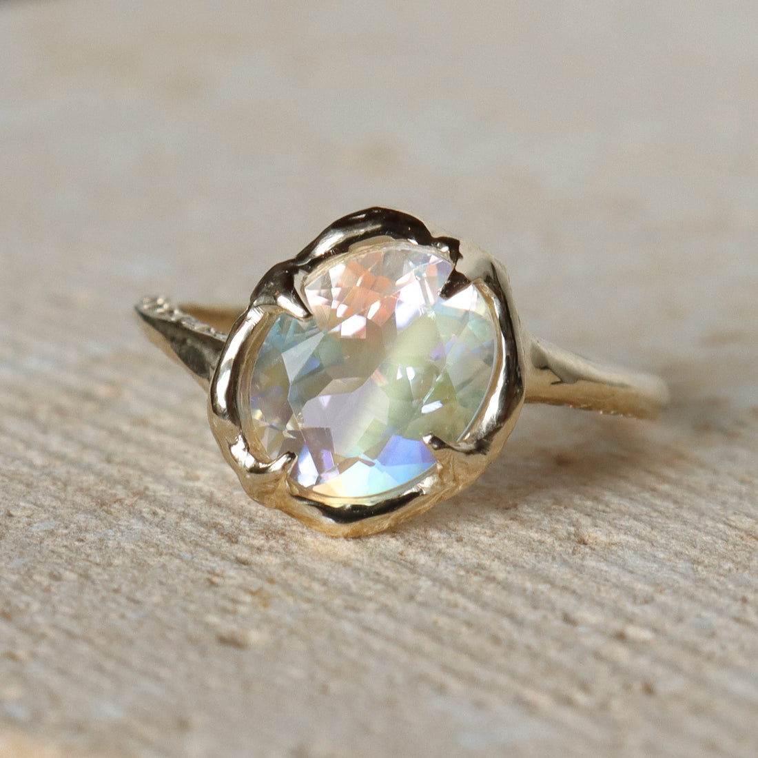 Gold ring with a large, faceted gemstone on a stone surface
