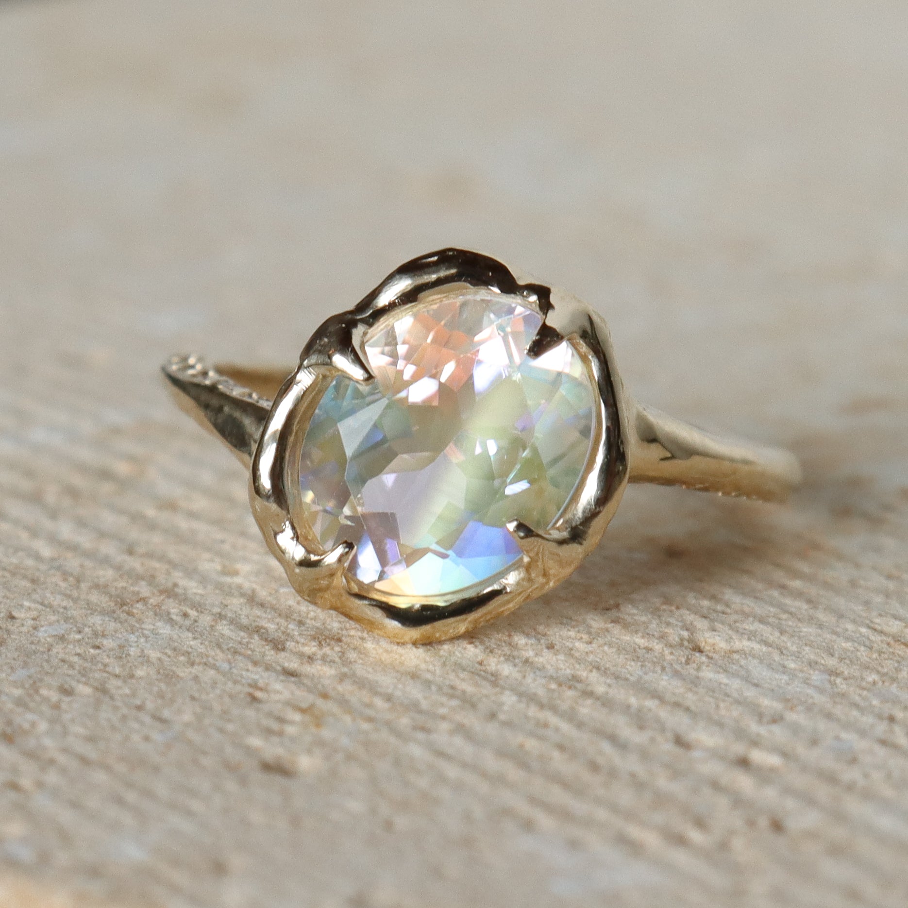 Gold ring with a large, faceted gemstone on a stone surface