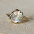 Gold ring with a large, faceted gemstone on a stone surface