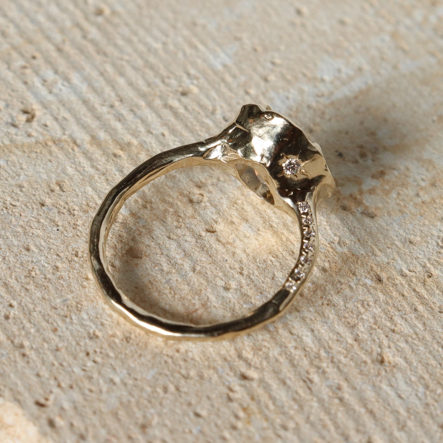 Gold ring with diamonds on a textured beige surface