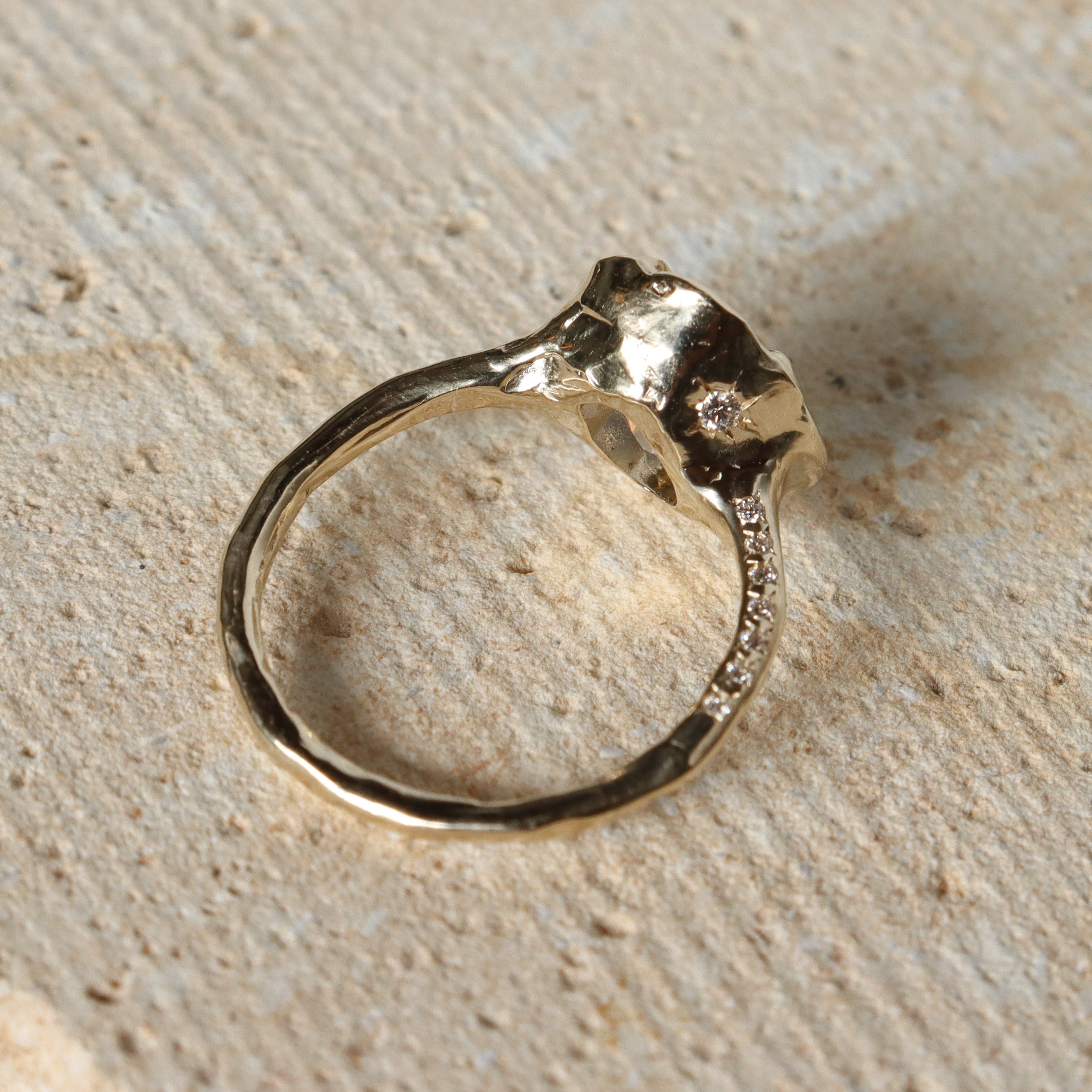 Gold ring with diamonds on a textured beige surface