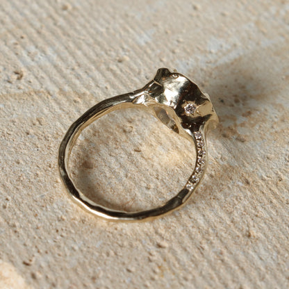 Gold ring with diamonds on a textured beige surface