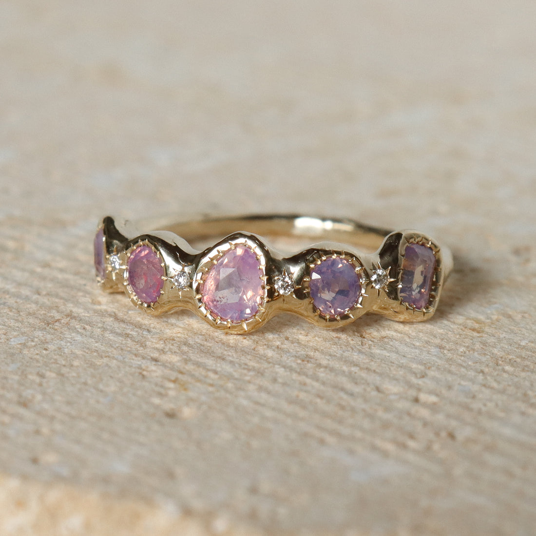 Gold ring with pink gemstones on a beige background