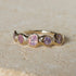 Gold ring with pink gemstones on a beige background