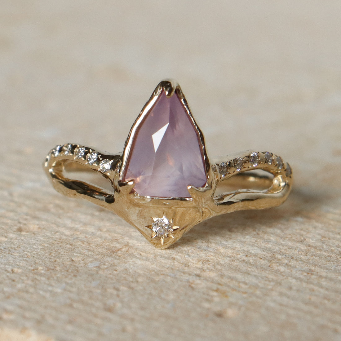 Gold ring with a pink gemstone on a stone surface