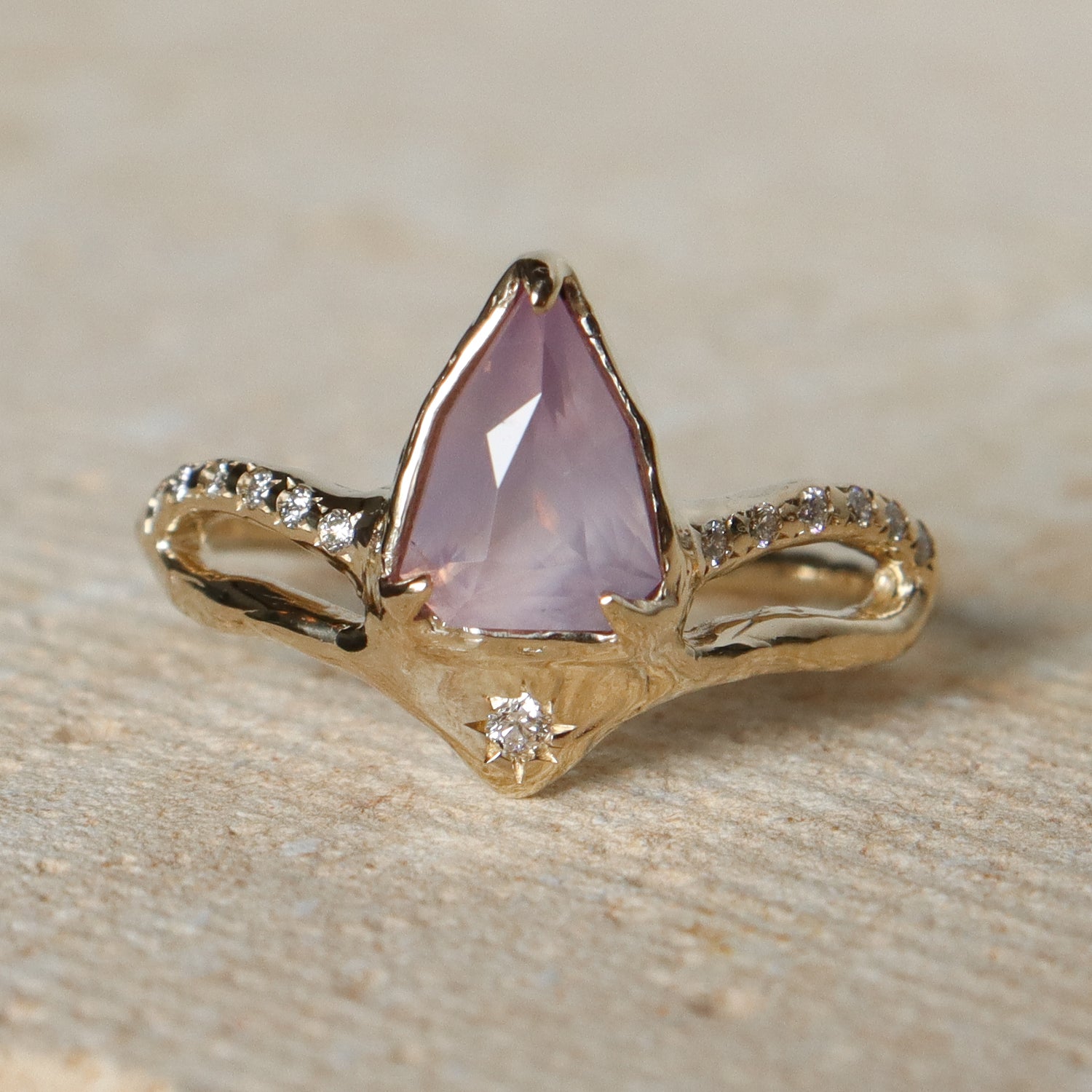 Gold ring with a pink gemstone on a stone surface