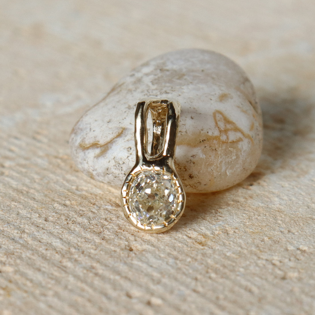 Gold pendant with a diamond on a stone surface