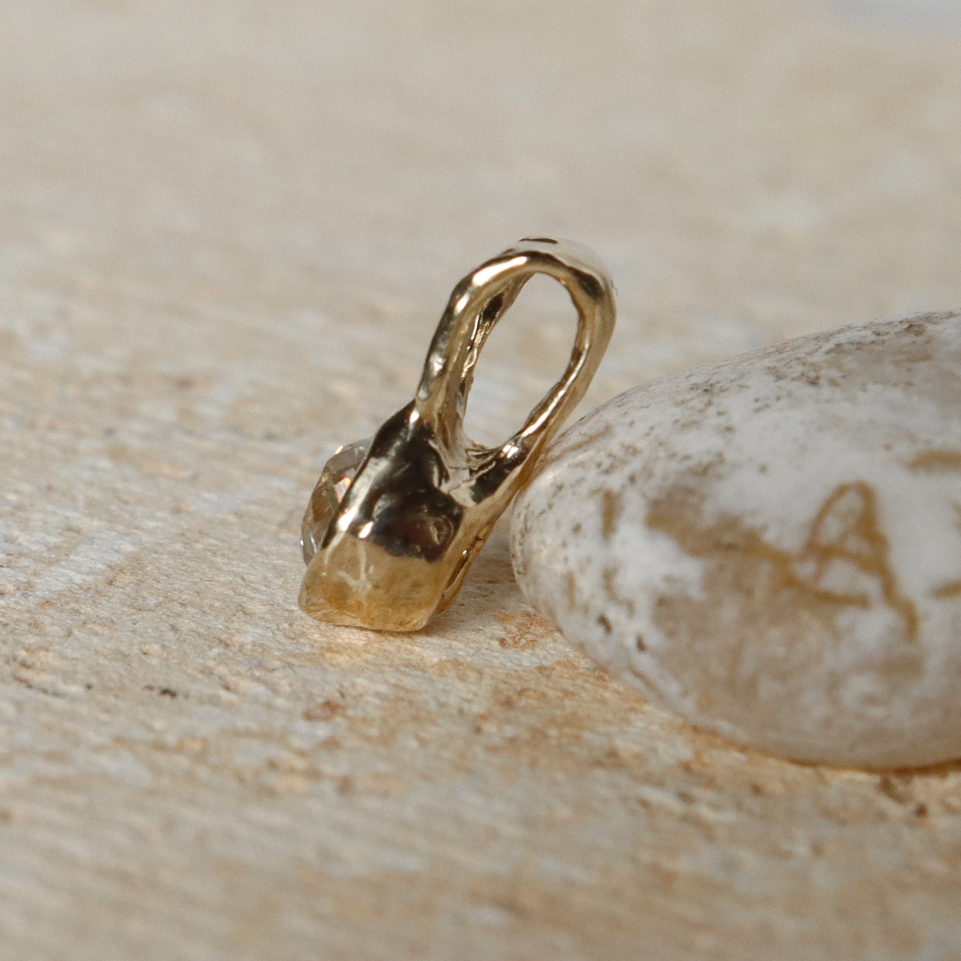 Gold pendant on a textured beige surface