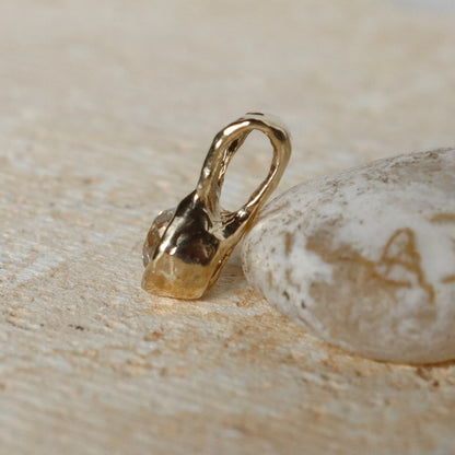 Gold pendant on a textured beige surface