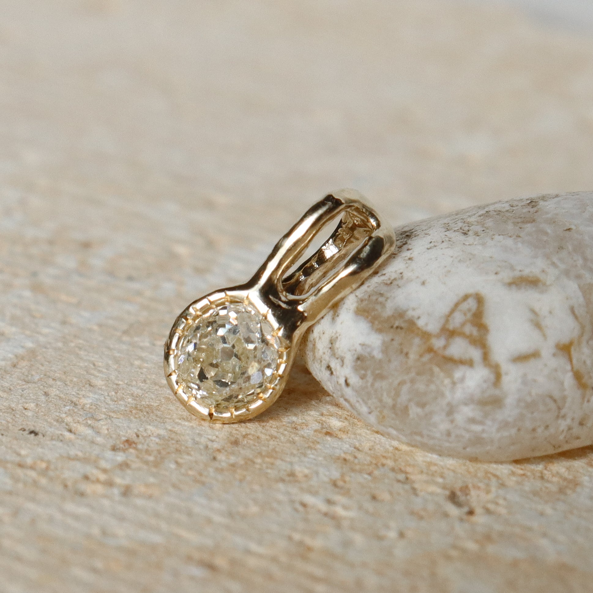 Gold pendant with a diamond on a stone surface