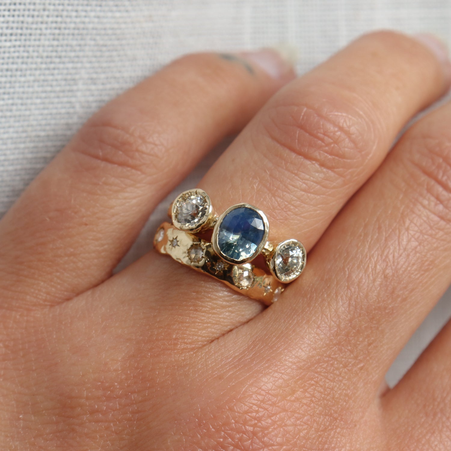 Gold ring with a blue gemstone and diamonds on a person&