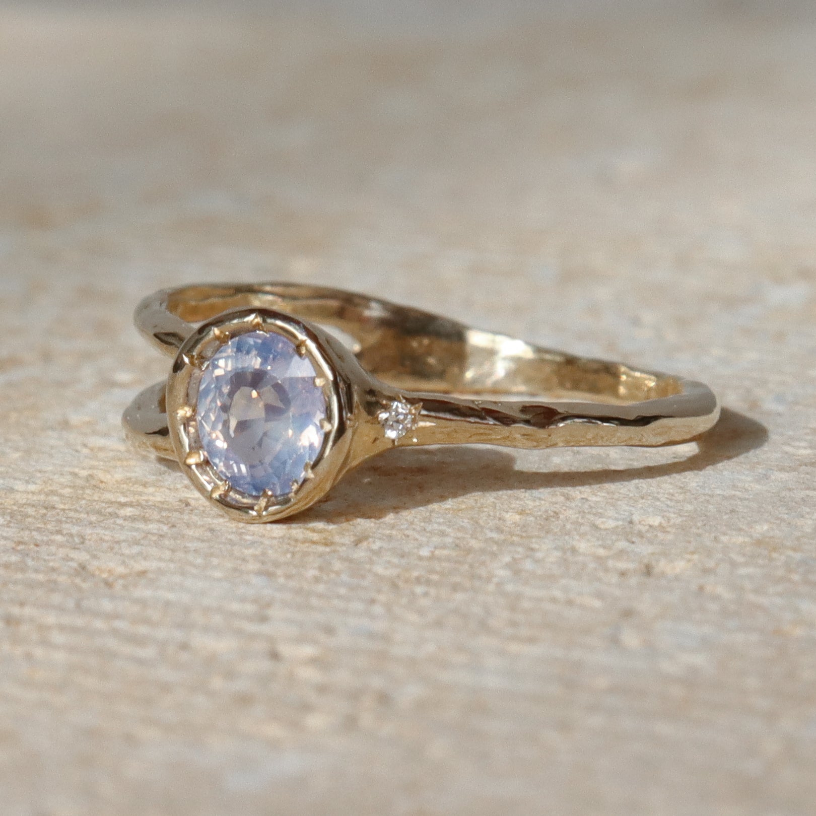 Gold ring with a central gemstone on a textured beige surface