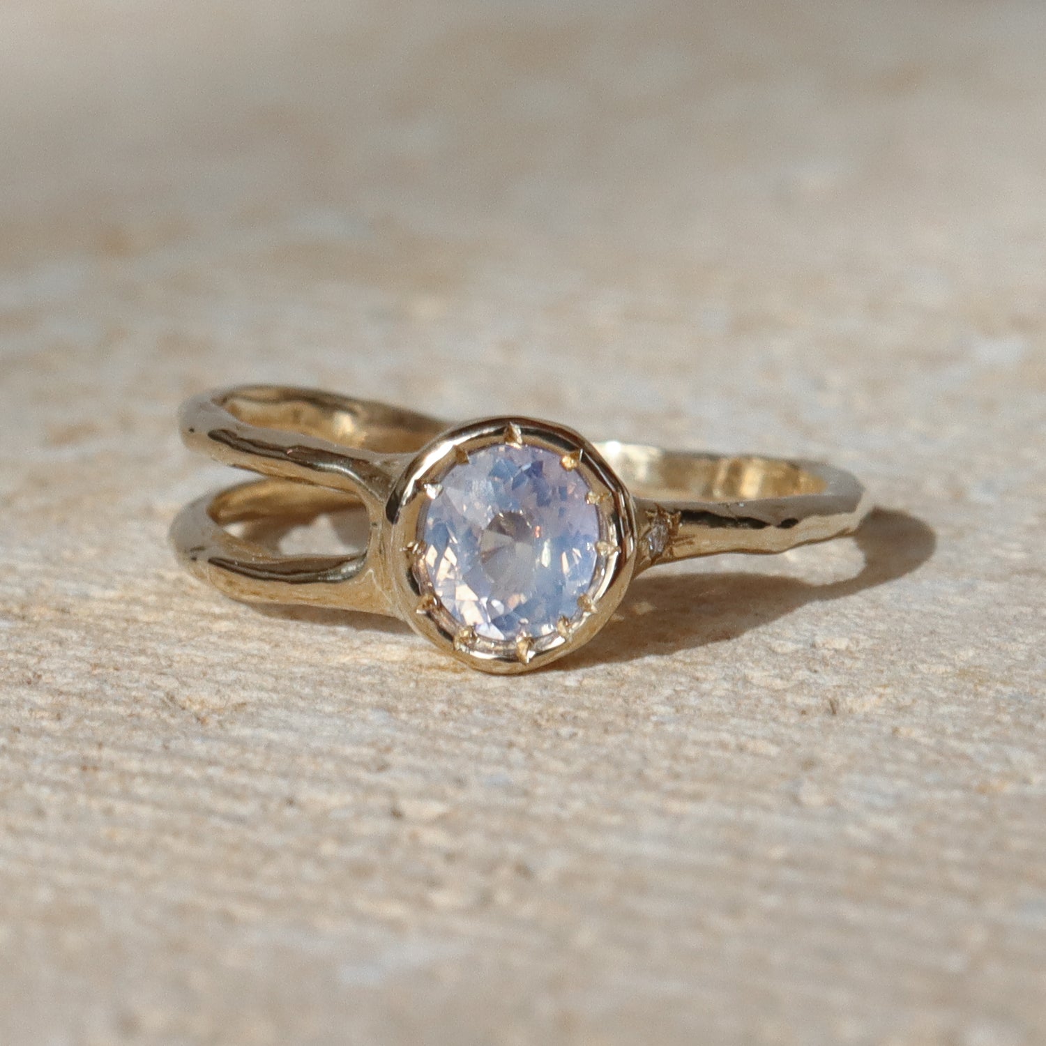 Gold ring with a central gemstone on a textured beige surface