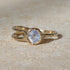 Gold ring with a central gemstone on a textured beige surface