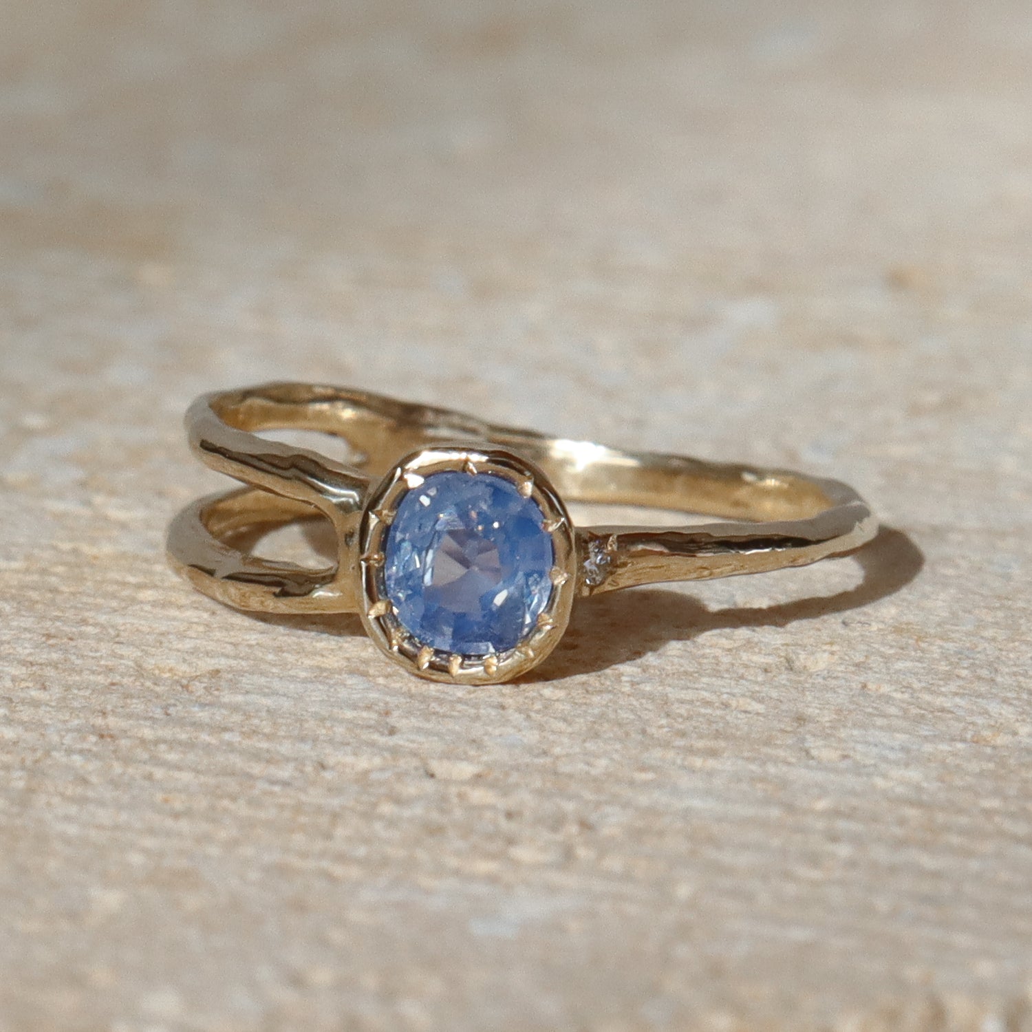 Gold ring with a blue gemstone on a beige surface