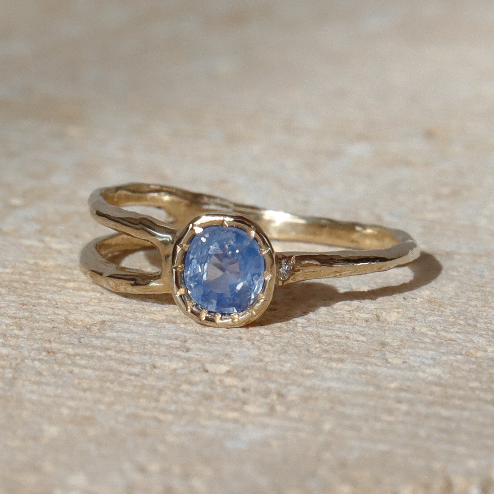 Gold ring with a blue gemstone on a beige surface