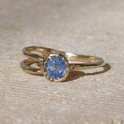 Gold ring with a blue gemstone on a beige surface